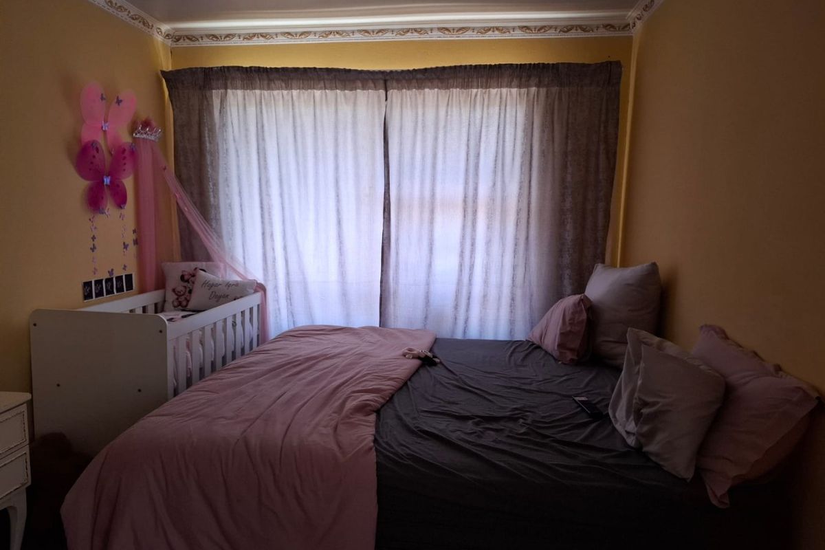 A bedroom featuring decorative ceiling cornicing and a large window with curtains.