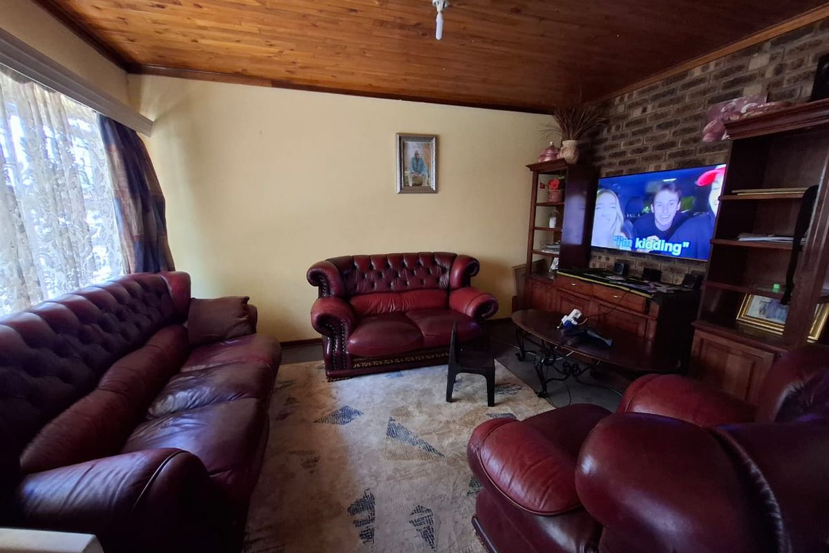 A living room featuring an exposed timber ceiling and a rustic exposed brick feature wall, providing a warm and traditional aesthetic.