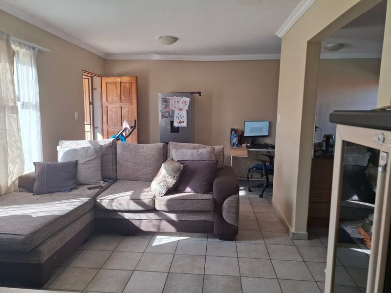 A living room area featuring tiled flooring and ceiling cornicing, providing a functional space with direct access to adjacent areas.