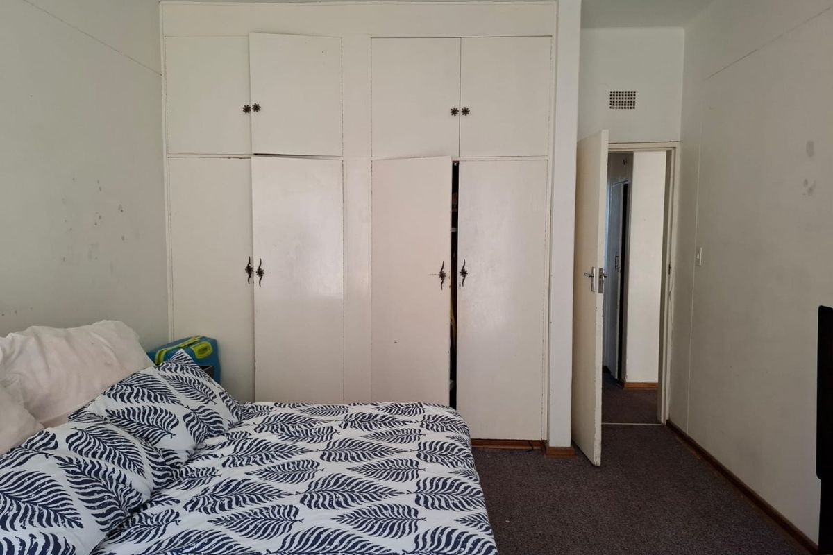 Bedroom featuring built-in cupboards and carpeted flooring, offering a functional space with potential for cosmetic updates.