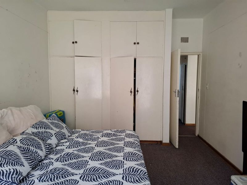 Bedroom featuring built-in cupboards and carpeted flooring, offering a functional space with potential for cosmetic updates.