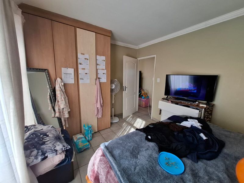 A bedroom featuring built-in cupboards, tiled flooring, and coved ceiling details, offering a functional space with standard finishes.