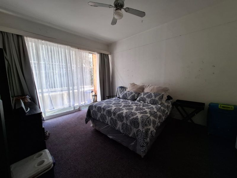 A bedroom featuring a ceiling fan, carpeted flooring, and a large sliding glass door providing access to an outdoor area.