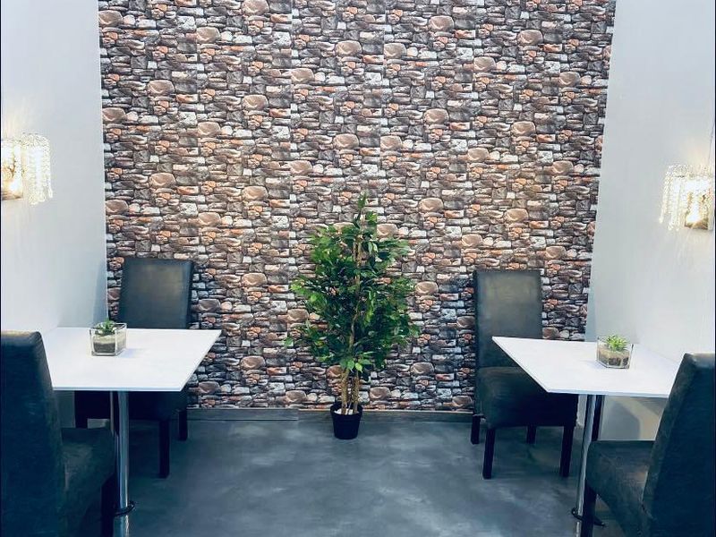 Dining area featuring a stone-effect feature wall, polished concrete flooring, and decorative wall-mounted crystal sconce lighting.