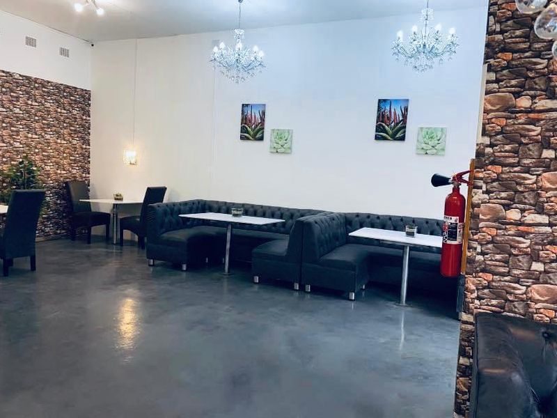 Commercial interior space featuring polished concrete floors, stone veneer accent walls, and elegant crystal chandeliers, suitable for a restaurant or lounge setting.