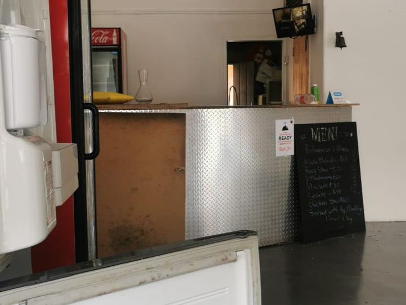 Commercial kitchen service area featuring a metal-clad counter, basic lighting, and functional service space suitable for food preparation or retail operations.
