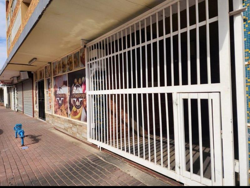 Commercial storefront featuring a secure metal gate, brick facade, and paved walkway access.