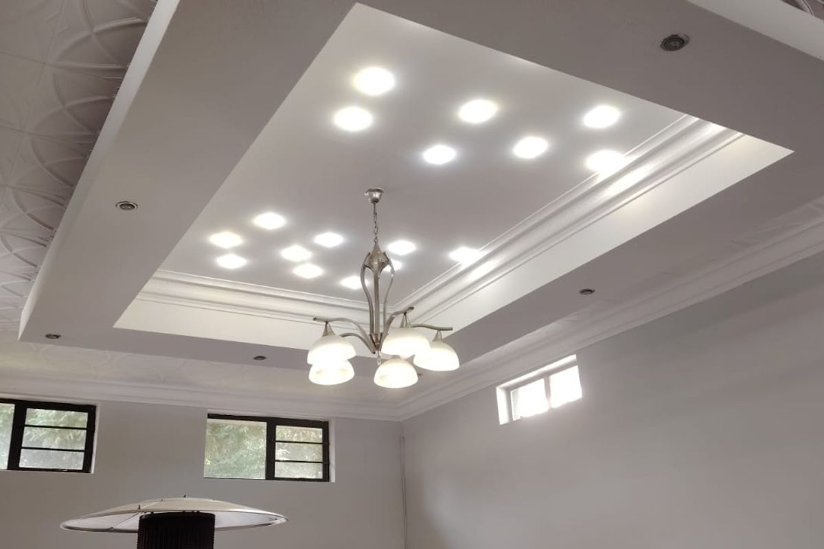 Spacious living area featuring a sophisticated coffered ceiling with recessed lighting, decorative ceiling tiles, and crown molding, providing a bright and modern atmosphere.