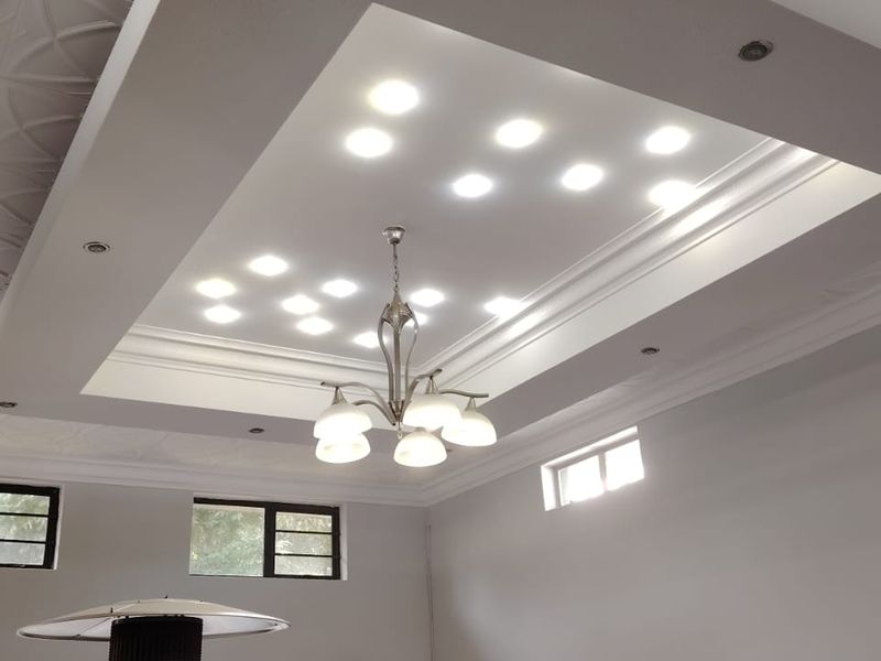 Spacious living area featuring a sophisticated coffered ceiling with recessed lighting, decorative ceiling tiles, and crown molding, providing a bright and modern atmosphere.