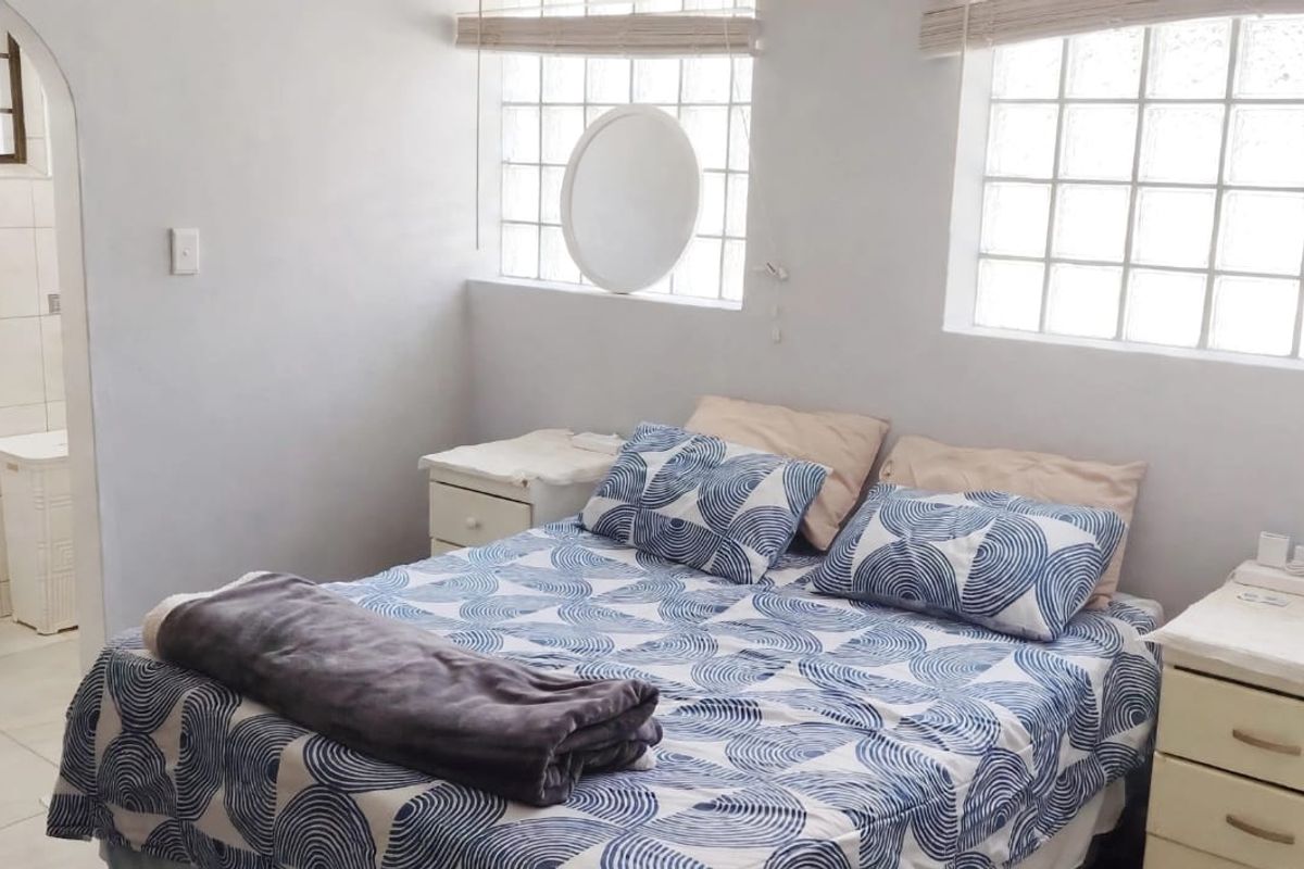 A bedroom featuring glass block windows and an adjoining en-suite bathroom with a pedestal basin and tiled flooring.