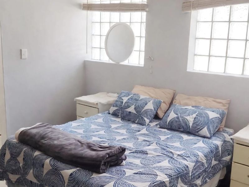 A bedroom featuring glass block windows and an adjoining en-suite bathroom with a pedestal basin and tiled flooring.