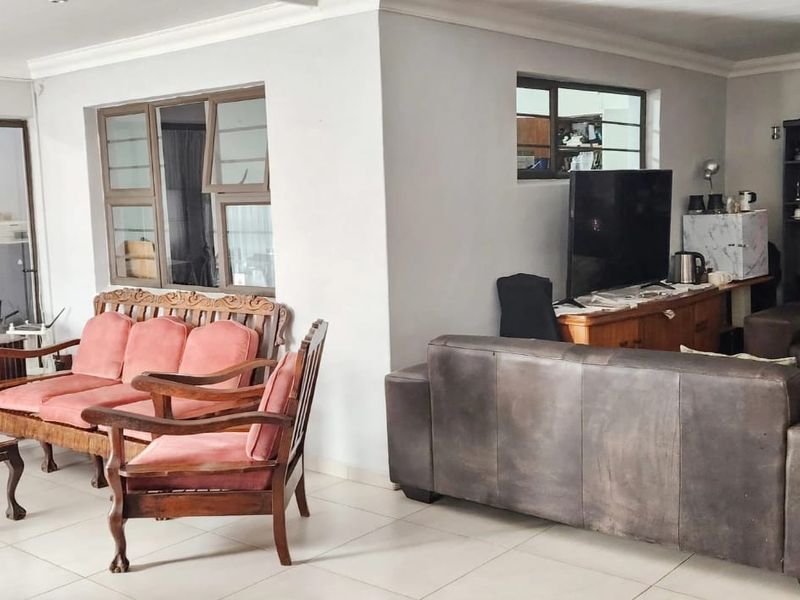 Spacious open-plan living area featuring neutral tiled flooring, recessed lighting, and large aluminium-framed windows providing ample natural light.