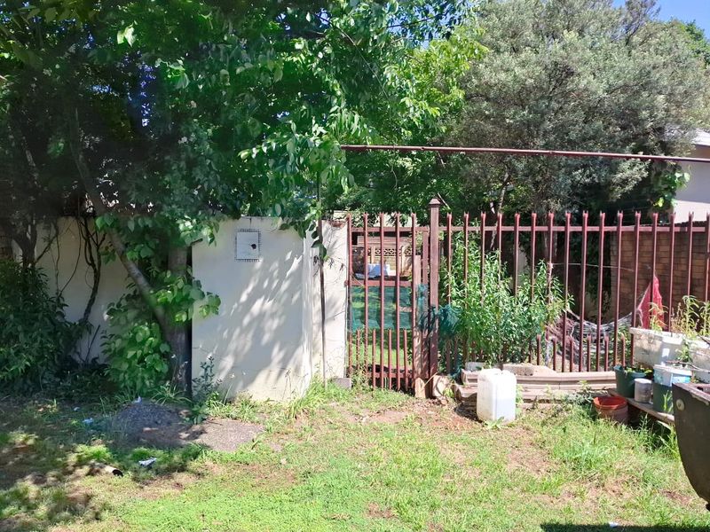 A view of the rear garden area featuring a perimeter wall and steel palisade fencing with a pedestrian gate.