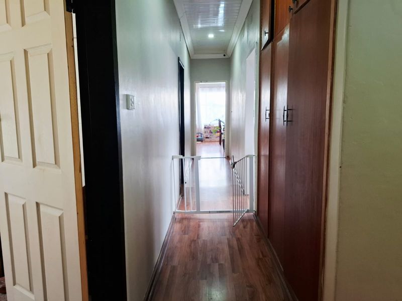 A functional hallway featuring laminate flooring and extensive built-in wooden cupboards for storage, connecting various rooms within the home.