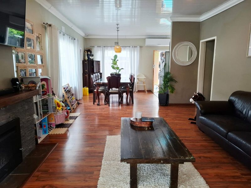Spacious open-plan living and dining area featuring warm laminate flooring, a fireplace, and a split-system air conditioner for year-round comfort.