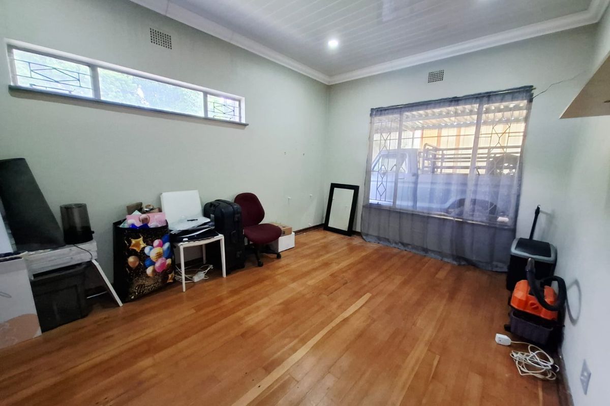 A living room featuring hardwood flooring, recessed lighting, and large windows with security bars, offering a functional space ready for modernization.