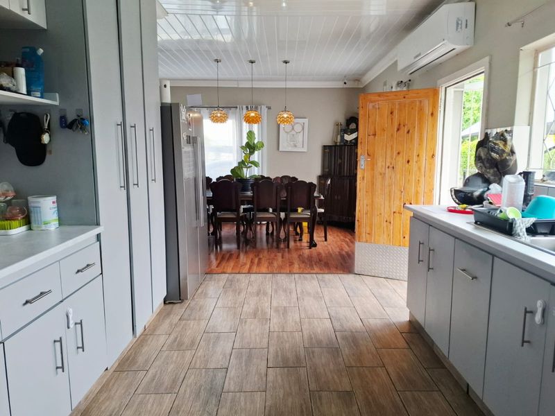 An open-plan kitchen and dining area featuring modern cabinetry, a mix of tiled and laminate flooring, and a split-system air conditioning unit.