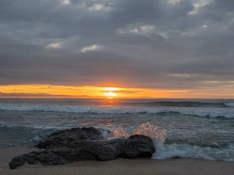 A scenic view of the ocean at sunset, showcasing the natural landscape and coastal environment of the property.