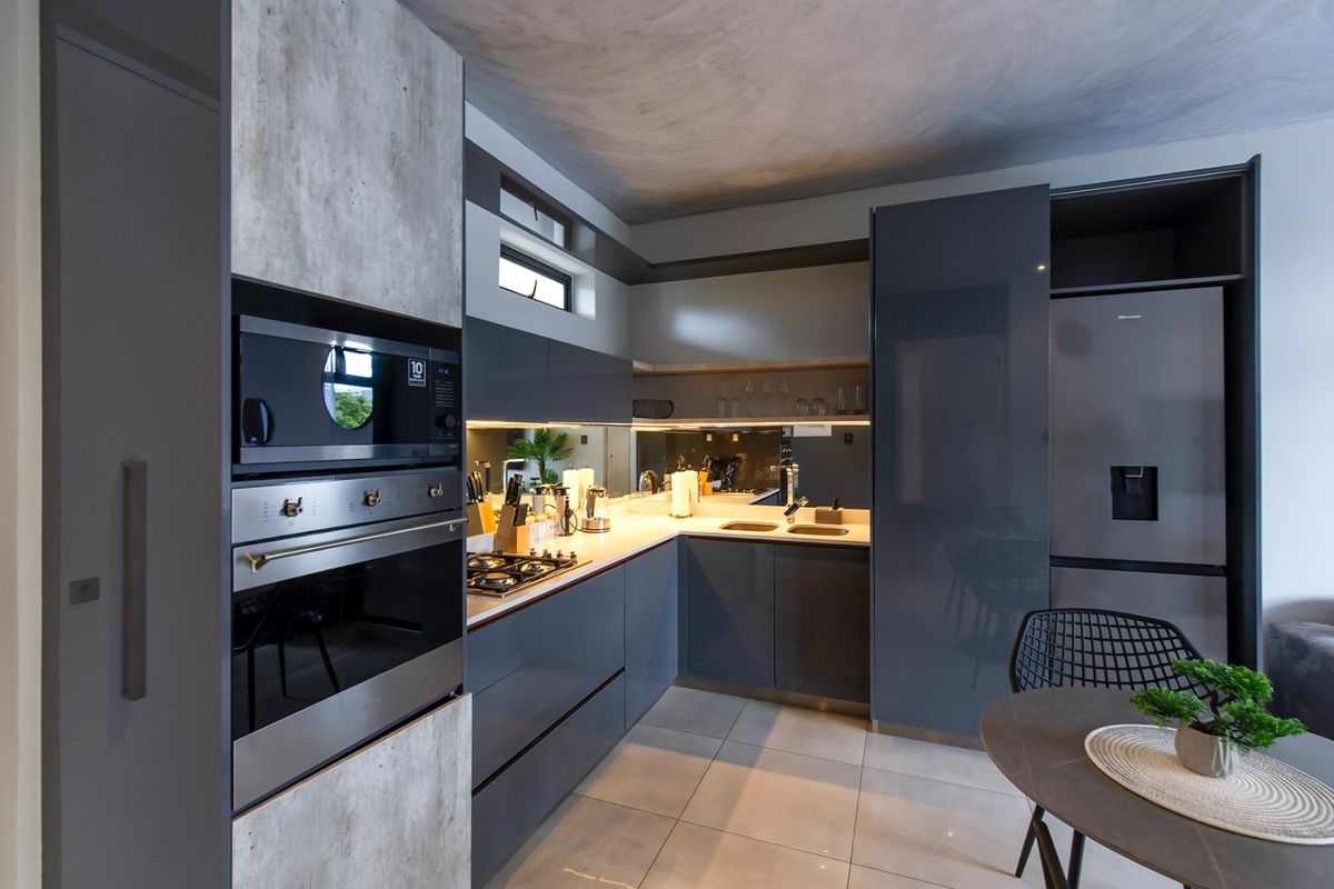 Modern kitchen featuring sleek grey cabinetry, stone countertops, integrated appliances, a gas hob, and a stylish mirrored splashback.