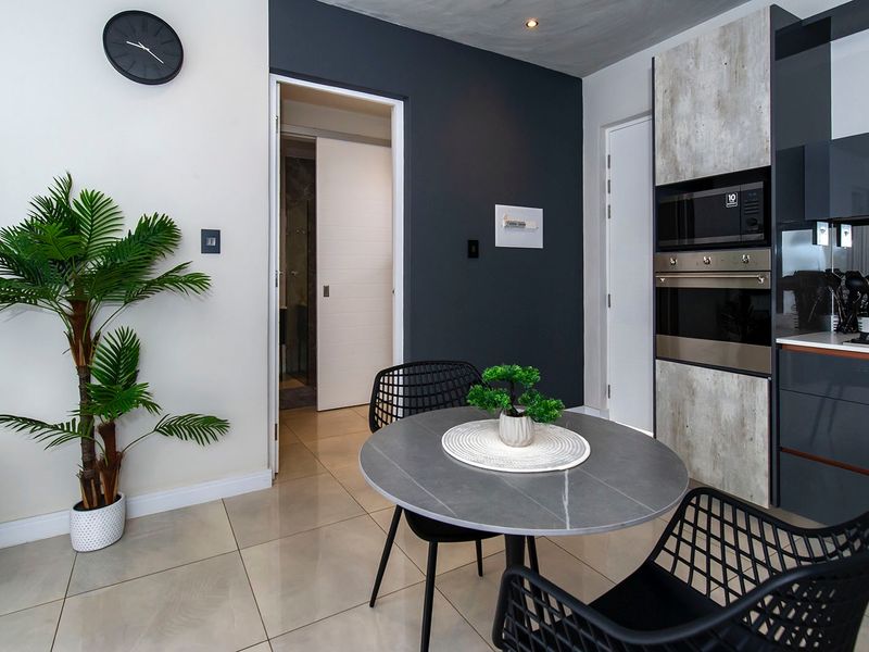 Modern open-plan living area featuring a sleek kitchen with built-in appliances, high-quality tiled flooring, and contemporary dark accent walls.