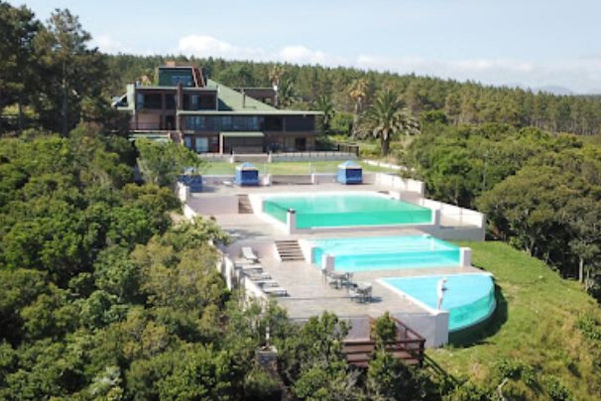 Aerial view of a large farm property featuring a multi-level swimming pool complex, expansive terraced patios, and a multi-story residence set within lush grounds.