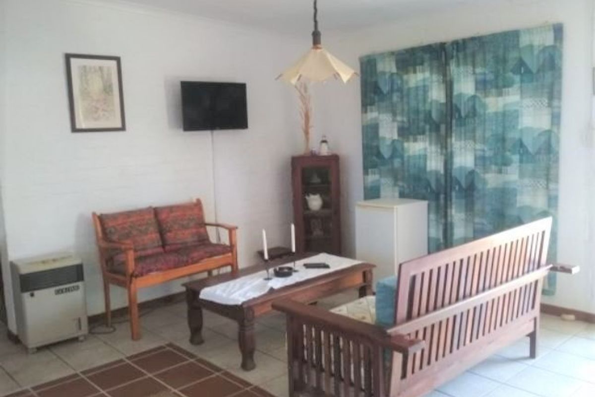 A functional living room area featuring tiled flooring and a central pendant light fixture, offering a blank canvas for potential interior updates.