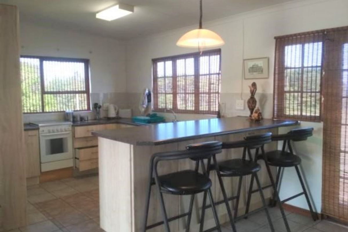 A functional kitchen featuring a central island with breakfast bar seating, laminate cabinetry, built-in oven, and tiled flooring with ample natural light.