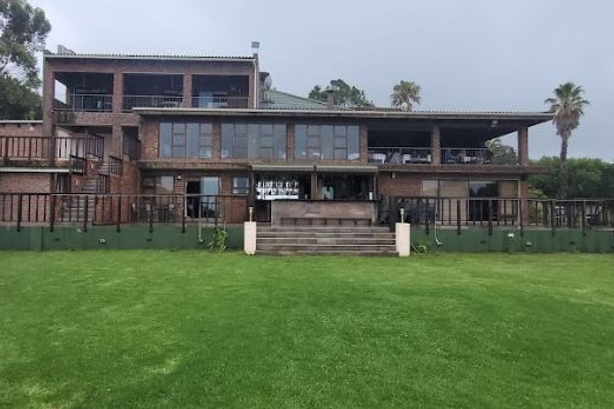 Rear view of a multi-story brick farmhouse featuring expansive balconies, large sliding glass doors, and a well-maintained lawn area.