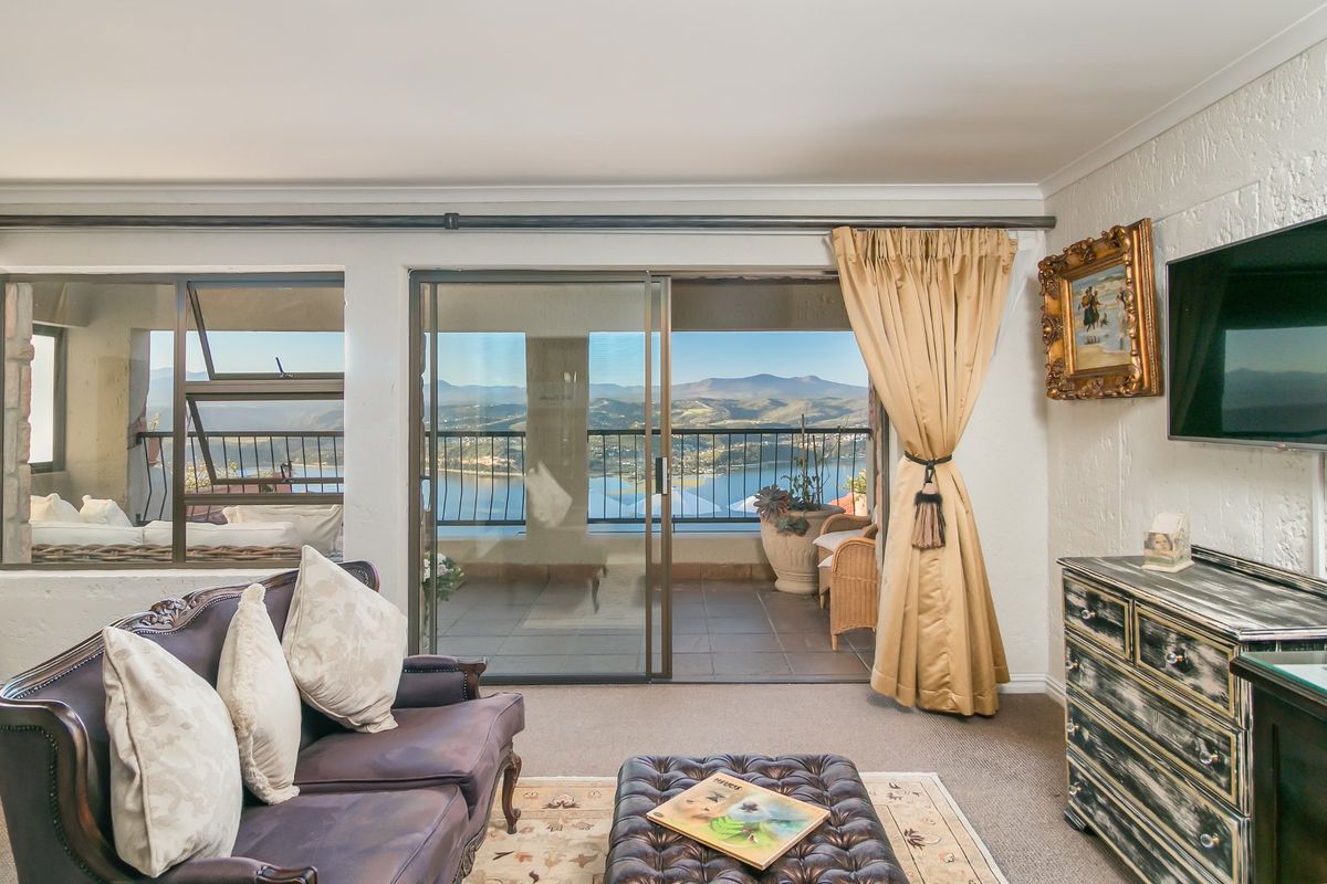 A comfortable living room featuring large sliding glass doors that open onto a balcony with scenic mountain and water views.