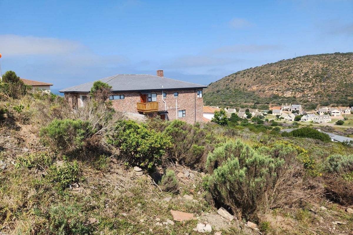 View of a residential property with brick facade and tiled roof, situated in a hilly landscape with surrounding neighborhood.