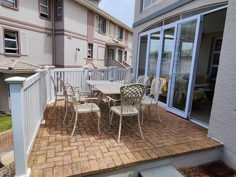 A paved outdoor patio area featuring a white balustrade and modern aluminium stacker doors providing access to the interior living space.