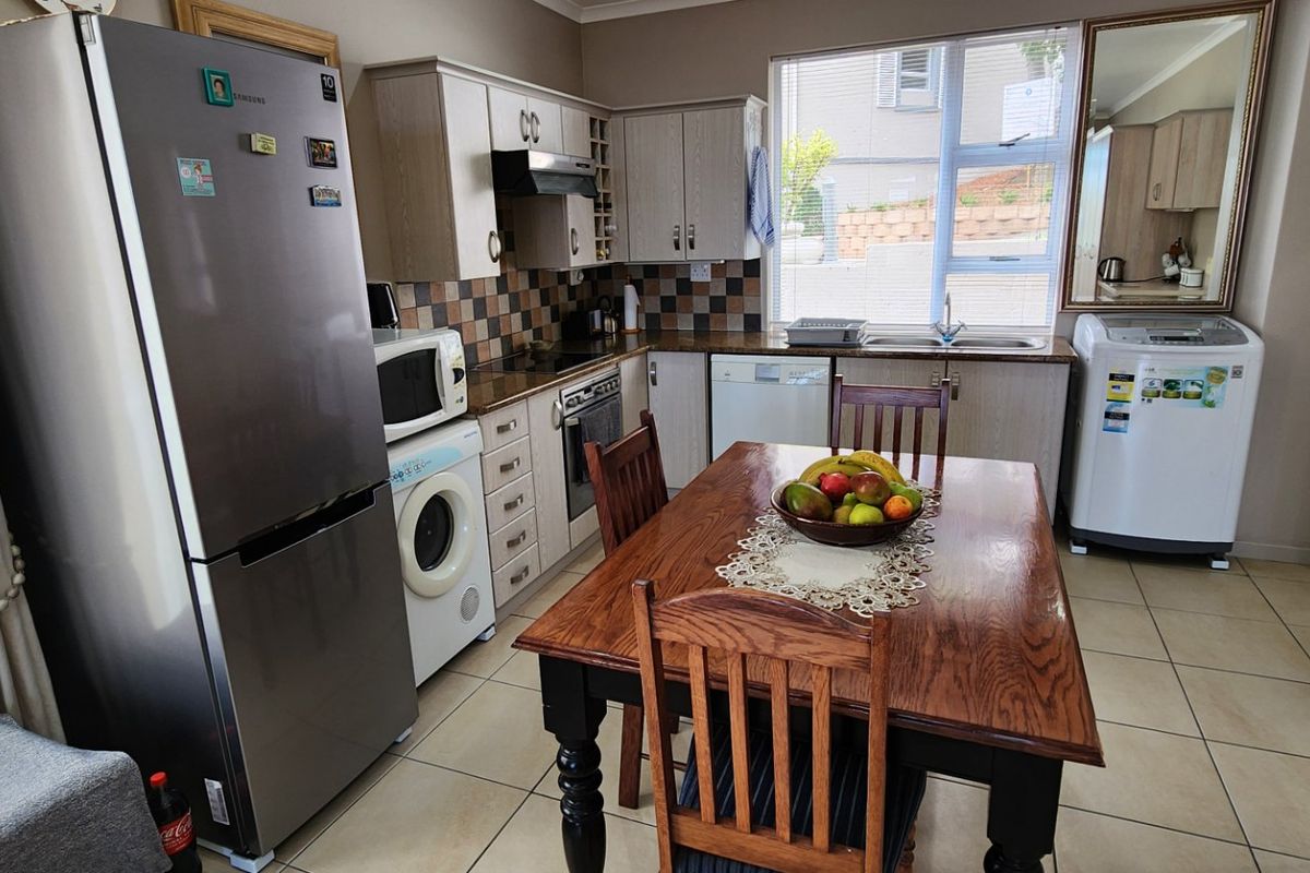 Functional kitchen featuring built-in cabinetry, tiled backsplash, integrated oven and hob, and tiled flooring, providing a practical space for cooking and dining.