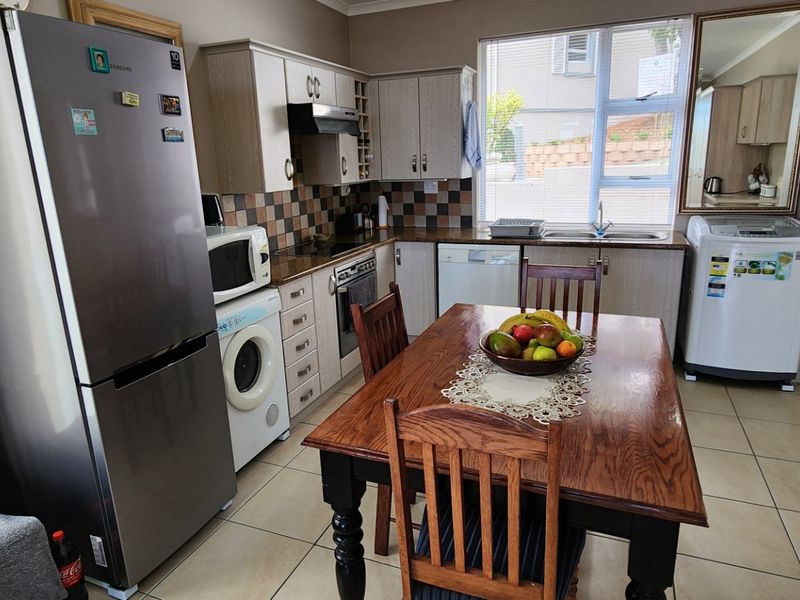 Functional kitchen featuring built-in cabinetry, tiled backsplash, integrated oven and hob, and tiled flooring, providing a practical space for cooking and dining.