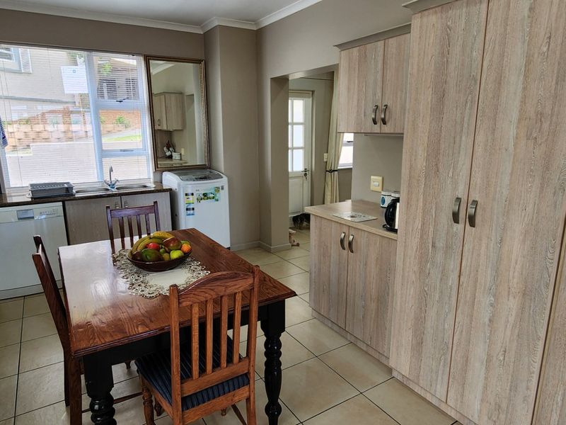 Open-plan kitchen and dining area featuring light wood-look cabinetry, tiled flooring, built-in oven, and ample storage space with a functional layout.