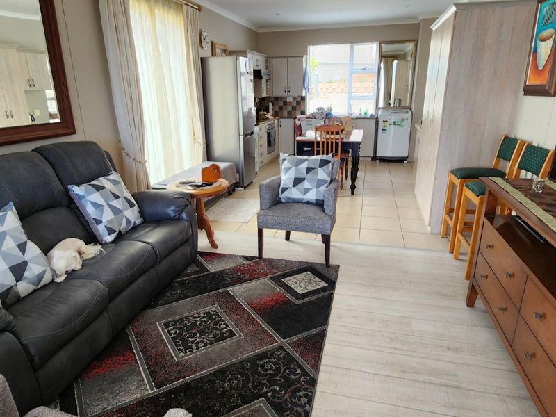 Open-plan living and kitchen area featuring a combination of tiled and laminate flooring, with functional built-in cabinetry and integrated kitchen appliances.