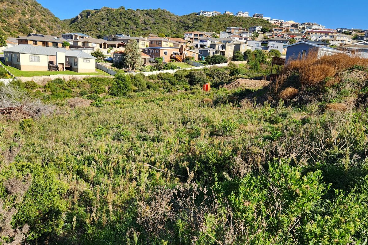 A view of a vacant residential plot featuring sloped terrain and natural vegetation, situated within an established neighborhood.