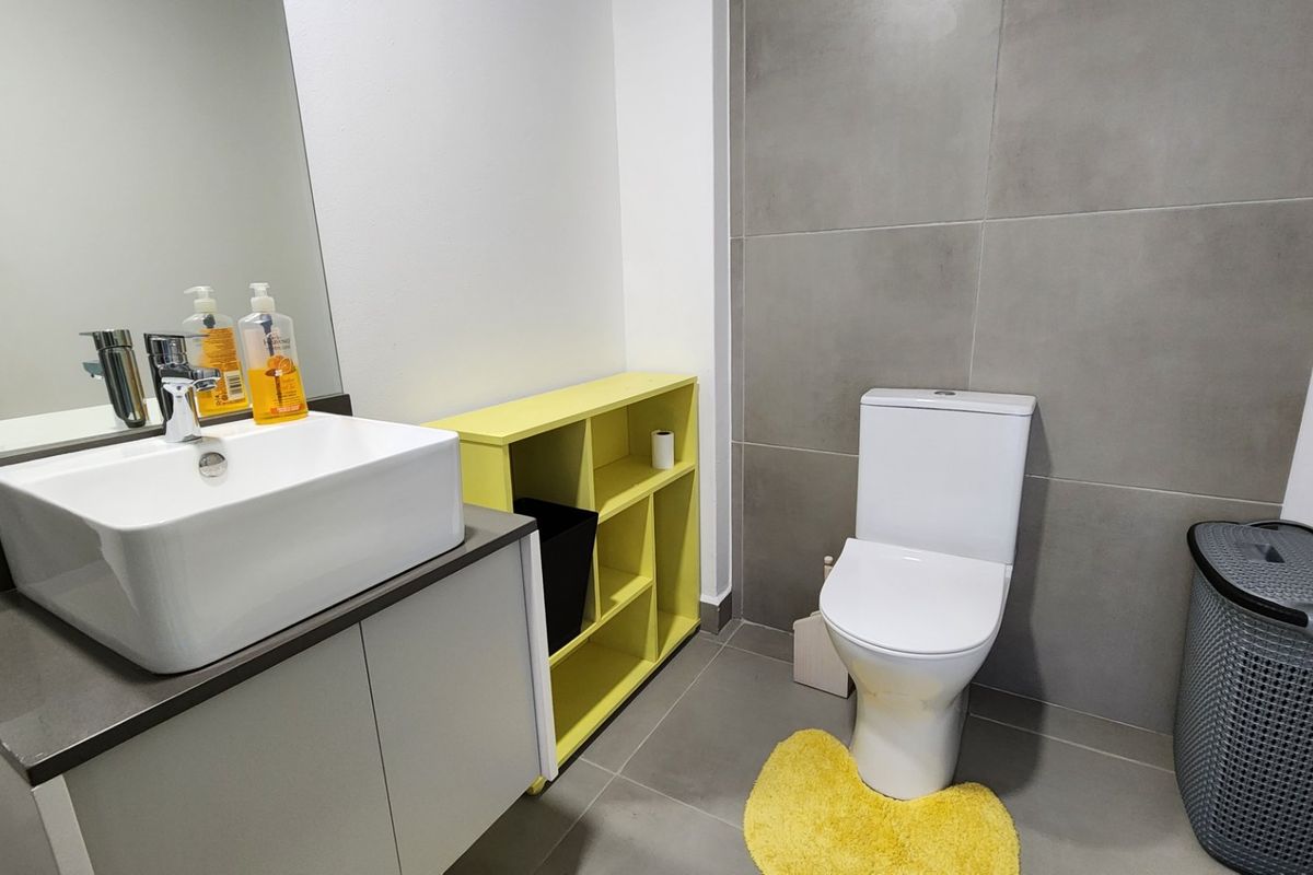 Modern bathroom featuring a vessel sink, vanity cabinet, wall-mounted mirror, and large format grey tiling.