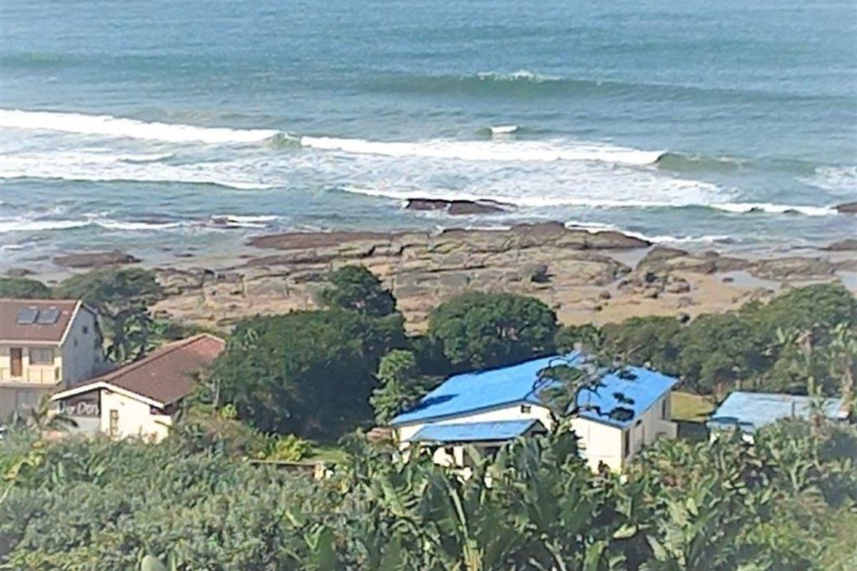 A scenic elevated view overlooking the coastline, rocky shore, and ocean waves, capturing the natural landscape and surrounding residential properties.