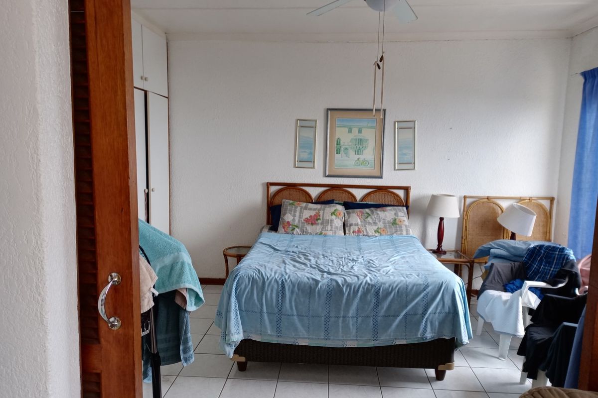 A bedroom featuring built-in cupboards, tiled flooring, and a ceiling fan, offering a functional and well-lit living space.