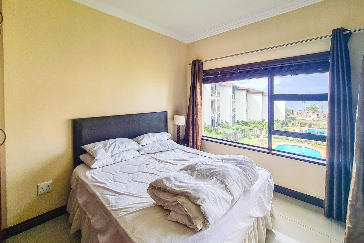 A bedroom featuring tiled flooring, cornice detailing, and a large window offering views of the complex pool area.