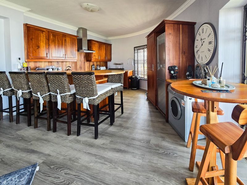 Open plan kitchen featuring warm wooden cabinetry, a breakfast bar, and durable laminate flooring, creating a functional and inviting living space.