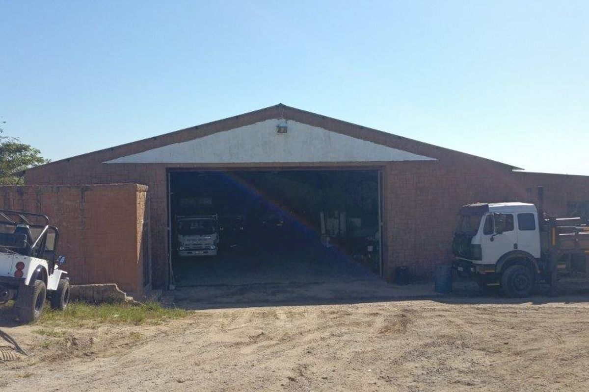 Front elevation of an industrial warehouse building featuring a large central access point and brick construction.
