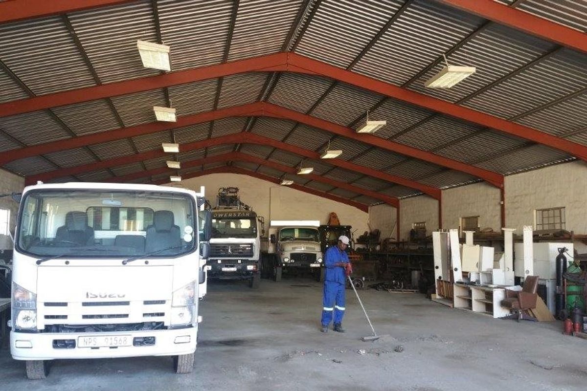Spacious industrial warehouse or garage featuring a high-clearance steel portal frame, corrugated metal roofing, and durable concrete flooring, suitable for heavy vehicle storage.
