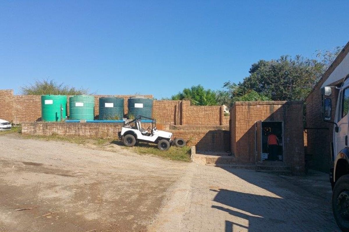 Rear industrial yard area featuring water storage tanks, brick boundary walls, and paved access space.
