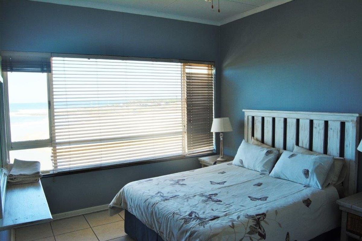 A bedroom featuring large windows with venetian blinds, tiled flooring, and a view of the exterior.