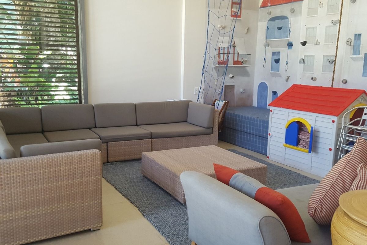A spacious living area featuring a built-in climbing wall and large louvre shutters, providing a versatile space for family activities.