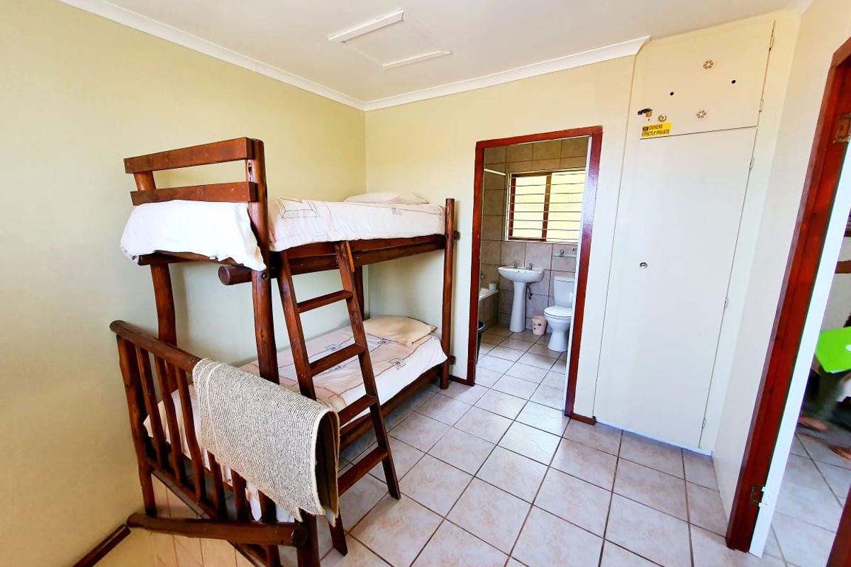 A bedroom featuring tiled flooring and a built-in cupboard, with an adjoining en-suite bathroom visible through the doorway.