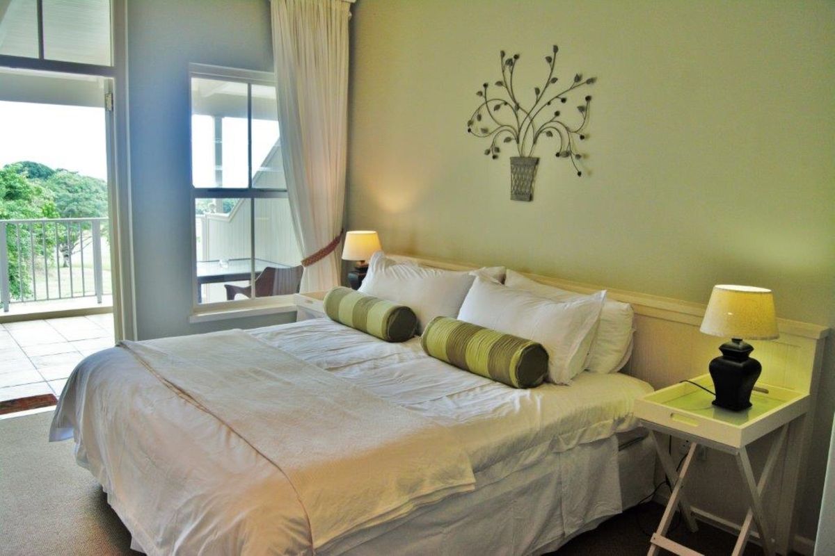 A well-maintained bedroom featuring carpeted flooring and direct access to a private balcony through a sliding glass door.