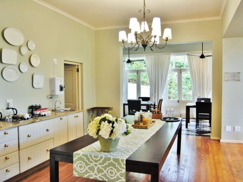 Spacious open-plan area featuring hardwood flooring, built-in cabinetry with granite countertops, and elegant chandelier lighting, leading to a bright dining space with french doors.