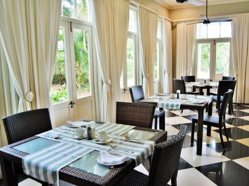 Bright dining area featuring classic checkered tile flooring, multiple sets of french doors providing garden access, and overhead ceiling fans.